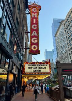 the chicago theatre marquee is lit up in red and yellow with people walking around