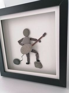 a shadow of a man with a guitar and rock in it's hand, framed in a black frame