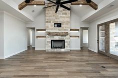 an empty living room with wood floors and a ceiling fan in the middle of it