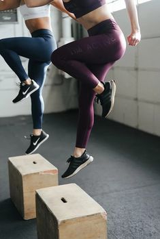 two women are jumping over blocks in the air with their hands on their hipss