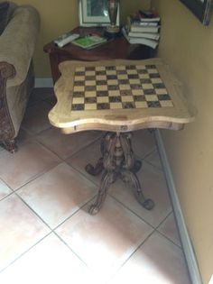 a chess board table sitting on top of a tile floor next to a couch and chair