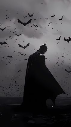 a black and white photo of a batman standing in front of bats flying above him