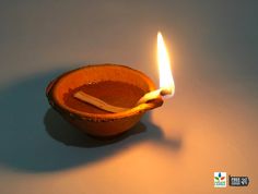 an orange bowl with a lit candle in it