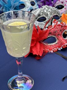 a glass filled with liquid sitting on top of a table next to masquerade masks