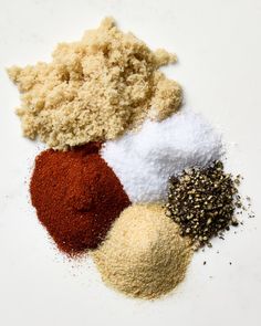 several different types of spices on a white surface with one red, the other yellow