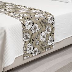 a bed with a white and brown flowered bedspread on top of it