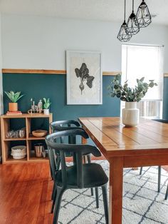 a dining room table with two chairs and a potted plant on the far wall