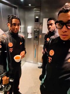 three men in black suits are holding bowls and looking at the camera