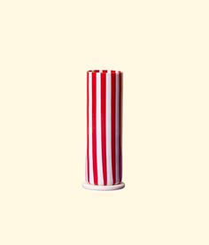 a red and white striped vase sitting on top of a table