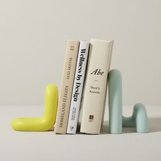 three books are lined up next to each other in front of a yellow bookend