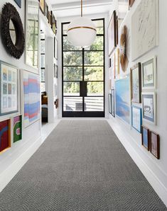 the hallway is lined with framed pictures and art on the walls, along with a gray carpet