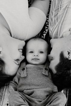 a black and white photo of a baby with his parents