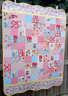 a pink and blue patchwork quilt hanging on a fence