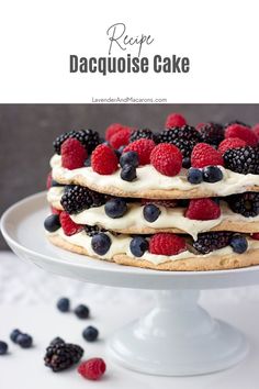 a cake topped with berries and cream on top of a white cake plate next to raspberries