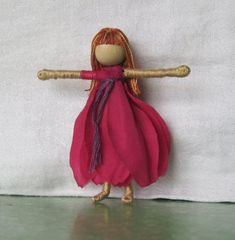 a doll is holding a wooden stick on a white surface with a towel in the background