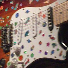 an electric guitar covered in lots of colorful stickers and magnets on it's body