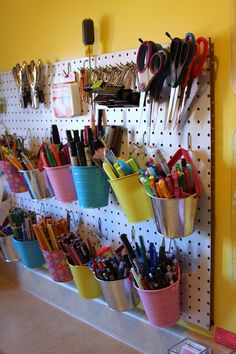 there is a pegboard with many pens and pencils on it in the room