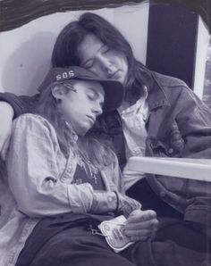 a man and woman sitting on a bed looking at a tablet computer while wearing baseball caps