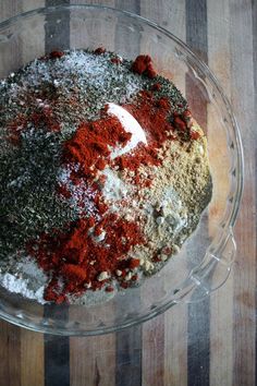 a glass bowl filled with spices on top of a wooden table