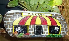 a painted rock sitting on top of a wooden table next to a potted plant