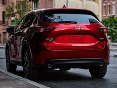 the back end of a red mazda cx - 5 parked on a city street