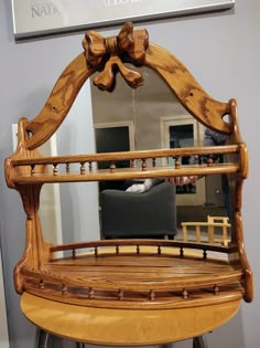 a wooden chair with a bow on it's back and mirror in the background