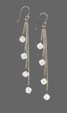 a pair of earrings with dangling chains and crystal stones, all in white gold plated metal