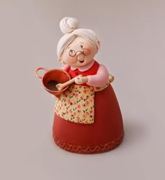 an old lady figurine is holding a pot and ladle in her hand