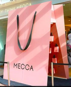 a pink shopping bag sitting in front of a store