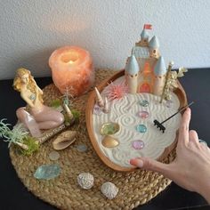 a person is holding their hand over a tray with various items on it and a lit candle in the background