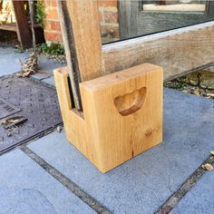 a wooden object sitting on top of a sidewalk next to a window sill and door