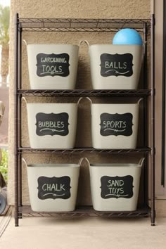 four buckets with chalkboard labels on them are sitting in front of a building