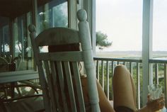 a woman sitting in a rocking chair on the porch