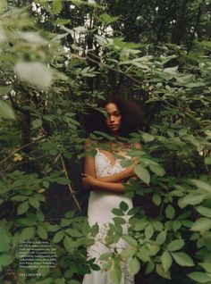 a woman standing in the woods with her arms crossed