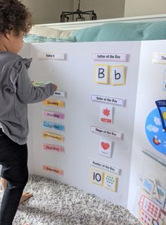 a little boy standing next to a white board with magnets on it