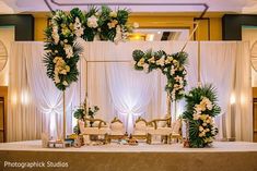 a table set up for a wedding with white flowers and greenery on the top