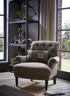 a chair sitting in front of a window next to a book shelf