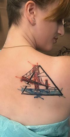 a woman with a watercolor tattoo on her upper back shoulder and the golden gate bridge in the background