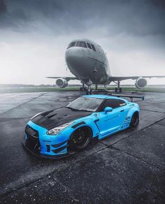 a blue sports car parked in front of an airplane