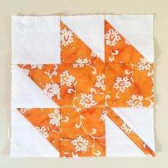 an orange and white quilt block with flowers on it