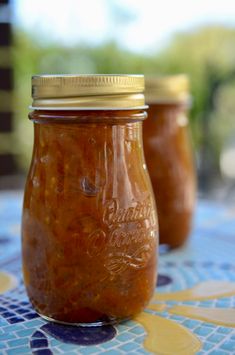 two jars filled with food sitting on top of a blue and yellow tiled tablecloth