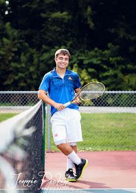 a young man holding a tennis racquet on top of a tennis court