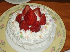 a cake with white frosting and strawberries on top is sitting on a plate