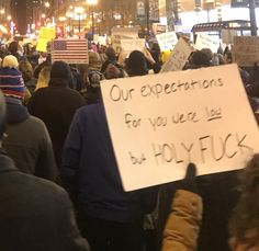 a group of people holding signs and standing in the middle of a street at night