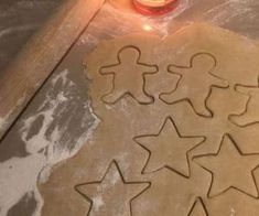 some cookies are sitting on a table next to a lit candle and cookie cutters