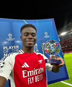 a young man holding up a trophy on top of a soccer field