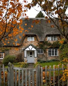 an old brick house with a thatched roof and white trim on the front door