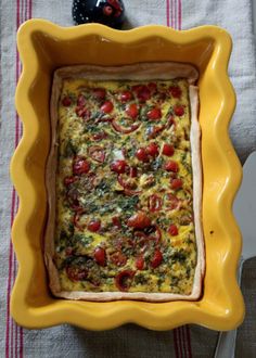 a square casserole dish with tomatoes and spinach in it on a table