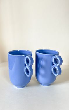 two blue coffee cups sitting next to each other