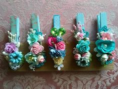 four flower clips are sitting on top of a wooden board with blue ribbon around them